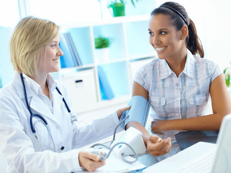 A physician checks a patient's blood pressure during a primary care visit